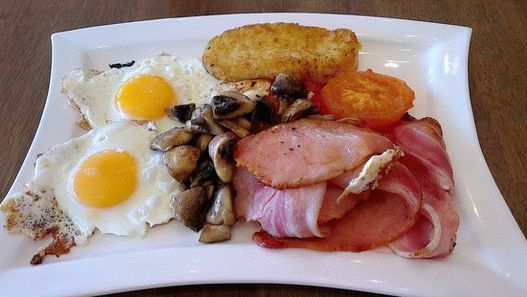 Foto irski doručak s prženim jajima, hash Browns i pečenom rajčicom